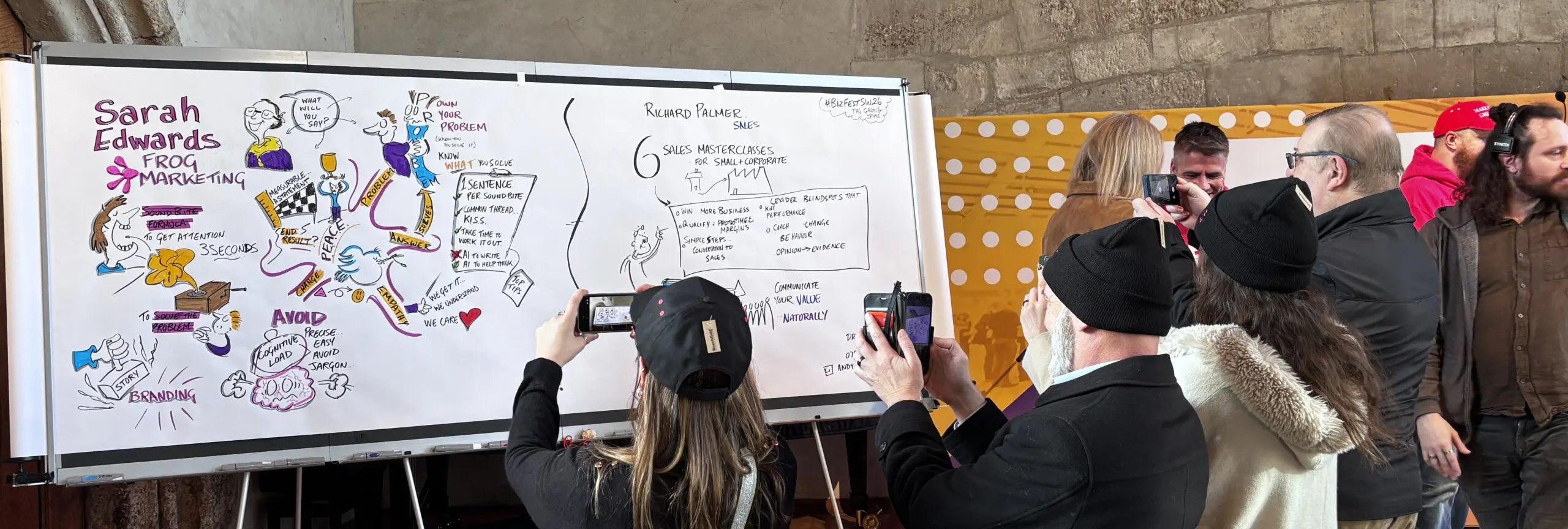A busy networking hall at BizFest SW, showing the live illustration board acting as a central focal point for delegate conversations and engagement.